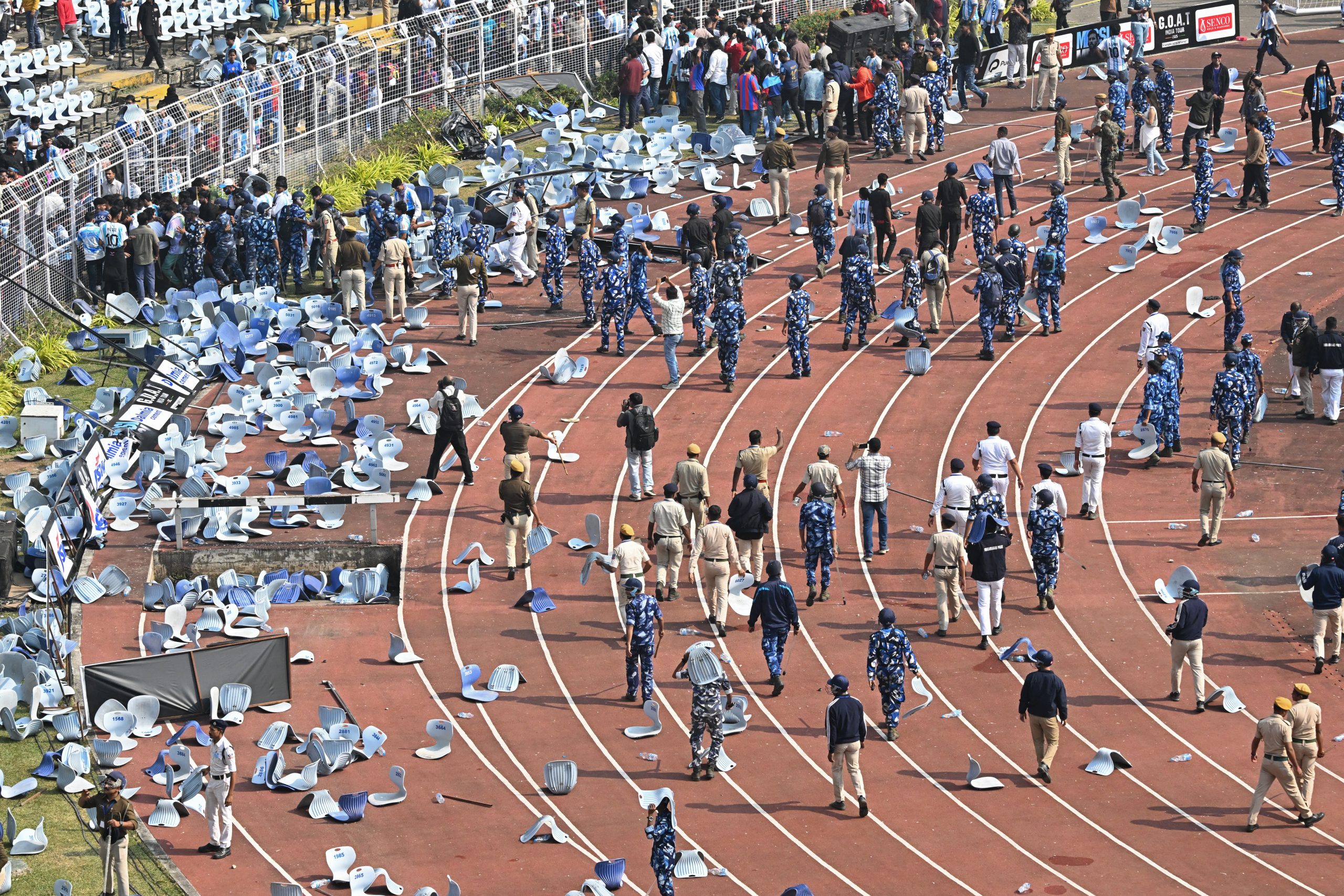 Security personnel try to control the crowd as Inter Miami's Argentine forward #10 Lionel Messi departs from the Salt Lake Stadium in Kolkata on December 13, 2025. Thousands of fans packed into a stadium in eastern India on December 13 to cheer on Lionel Messi as the football legend unveiled a 21-metre (70-foot) statue of himself. (Photo by Dibyangshu SARKAR / AFP)
