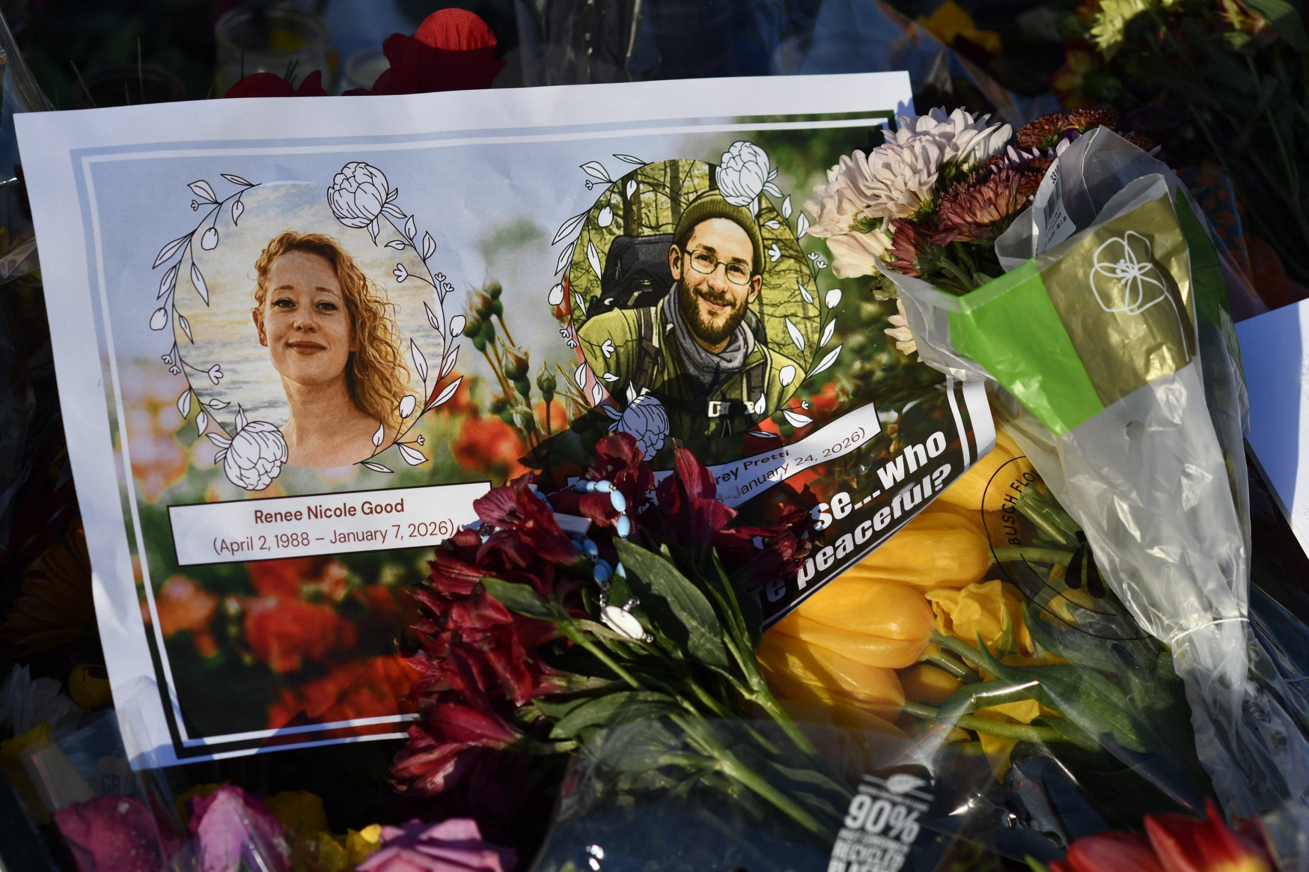 A card with images of Renée Good and Alex Pretti lies among flowers and other mementos at a memorial in Minneapolis, Minnesota, on January 27, 2026. On January 24, federal agents shot and killed Alex Pretti, a 37-year-old ICU nurse, while scuffling with him on an icy roadway in Minneapolis, less than three weeks after an immigration officer fired on Renee Good, also 37, killing her in her car. The fatal shootings has reignited accusations that federal agents enforcing US President Donald Trump's militarized immigration crackdown are inexperienced, under-trained and operating outside law enforcement norms. (Photo by Octavio JONES / AFP)